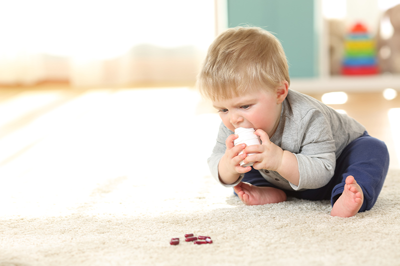 Baby in danger playing with a bottle of medicines