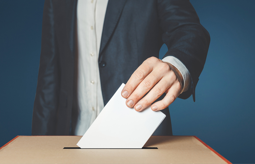man putting ballot into voting box