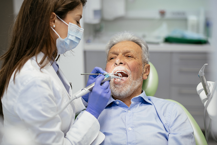 man in dentist chair with woman dentist working on him