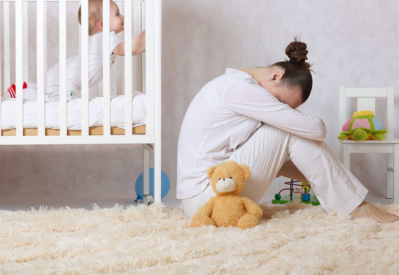 Mother depressed by baby in crib.