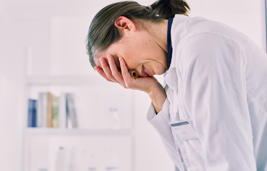 doctor leaning over with hand on face seeming stressed