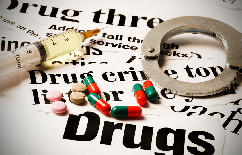 paper with words about drugs on it with handcuffs and drugs