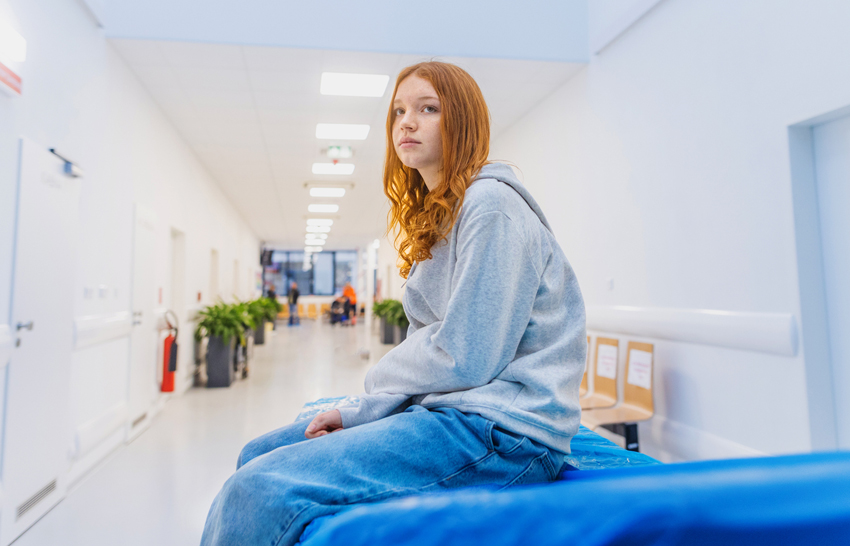 teenage girl sitting on a hospital bed waiting in the lobby
