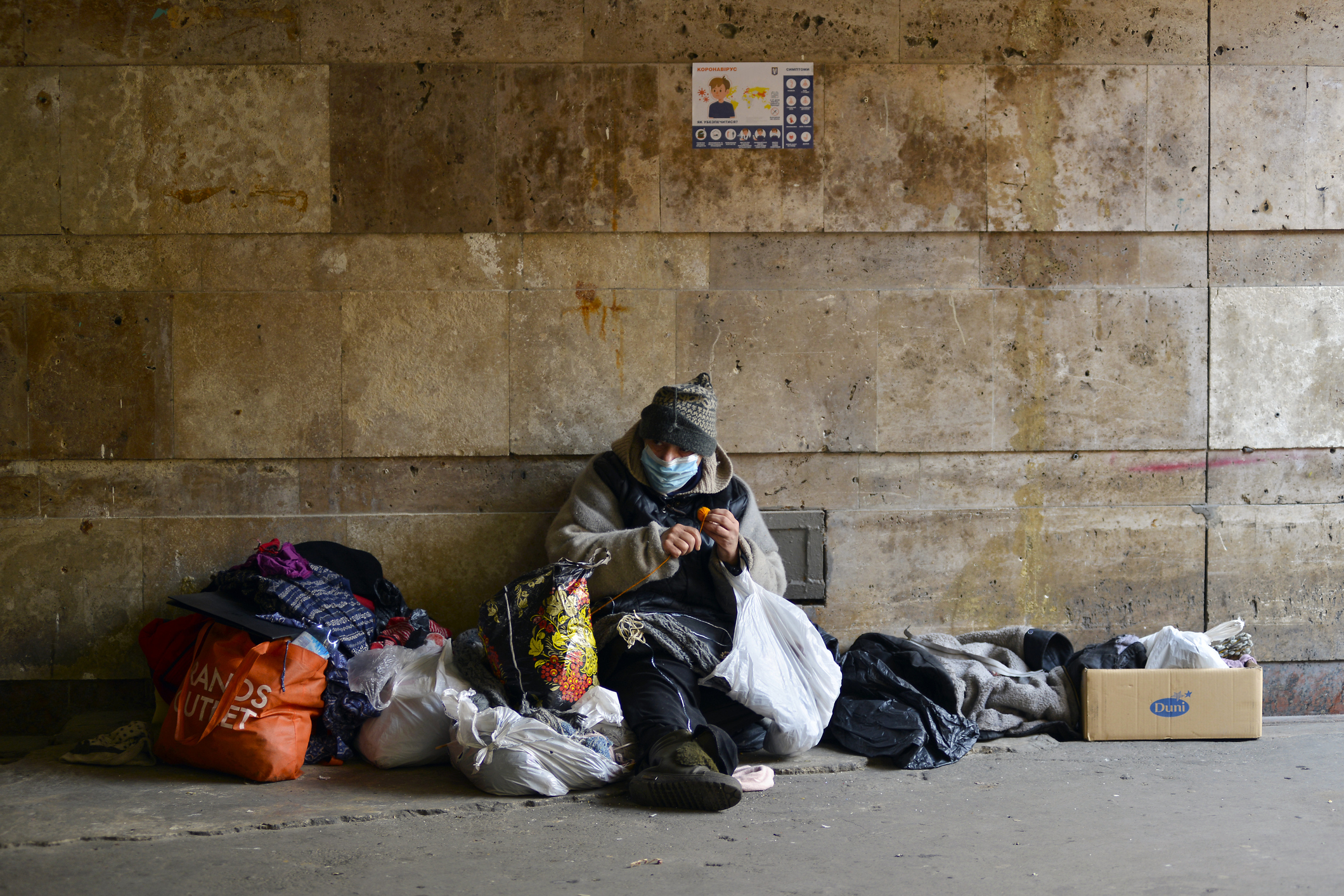 homeless man with his possessions in tunnel