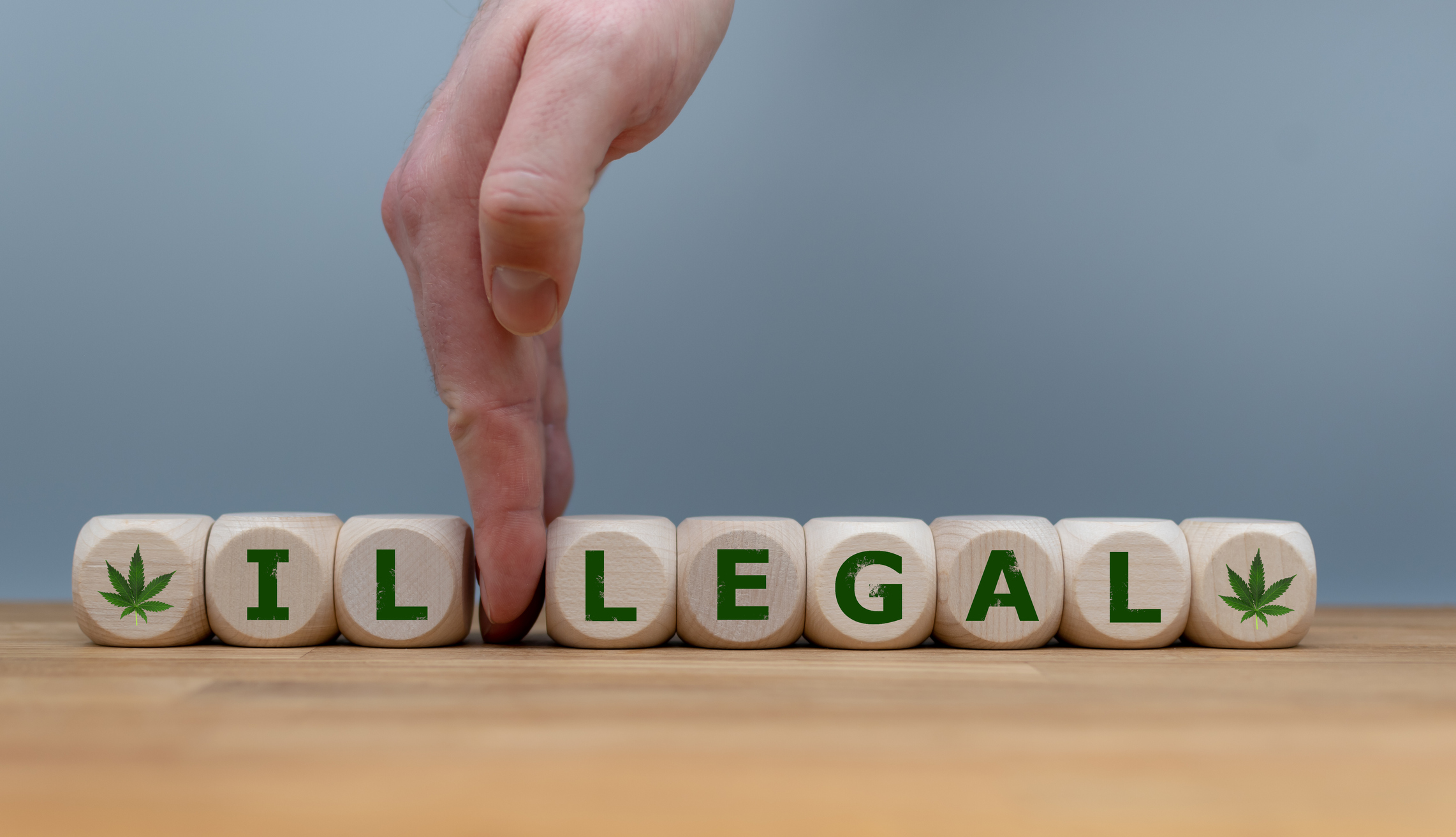 Dice form the word "ILLEGAL" while a hand separates the letters "IL" in order to change the word to "LEGAL"