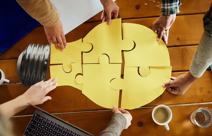 Above view of unrecognizable creative team cooperation while making light bubble of puzzles at casual office.