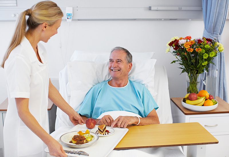 Man in Hospital Bed receiving food from nurse