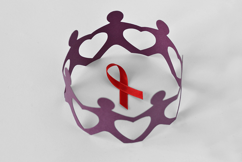 paper cutout of people in circle around red HIV red ribbon