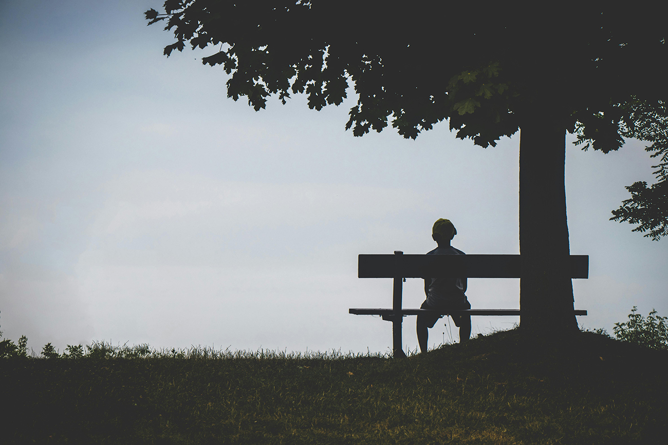 someone sitting on a bench in a park in silhouette