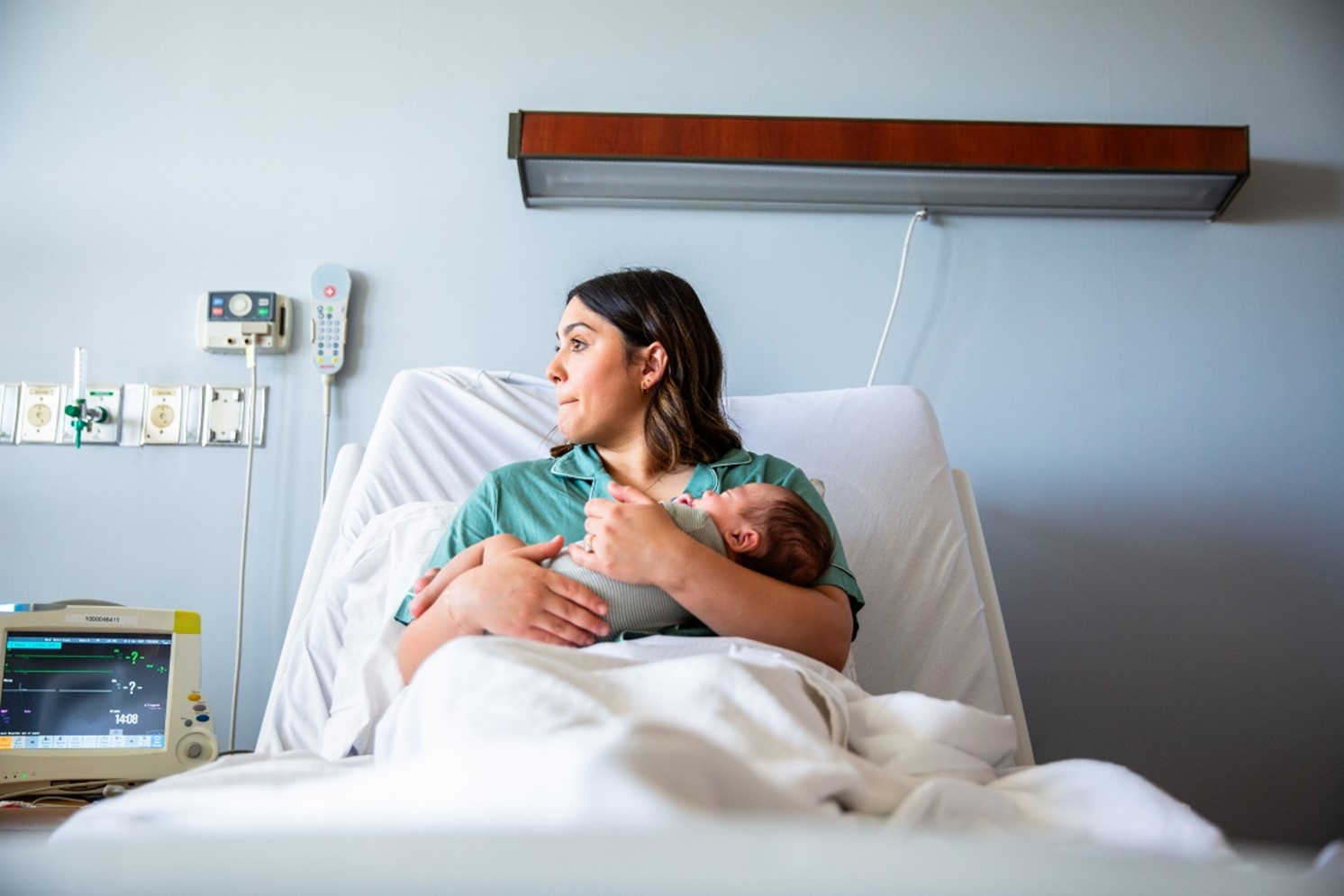 female patient on a hospital bed holding a child in her arms