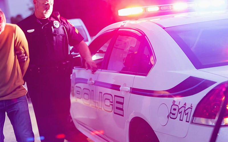 Police oficer arresting a young man at night 