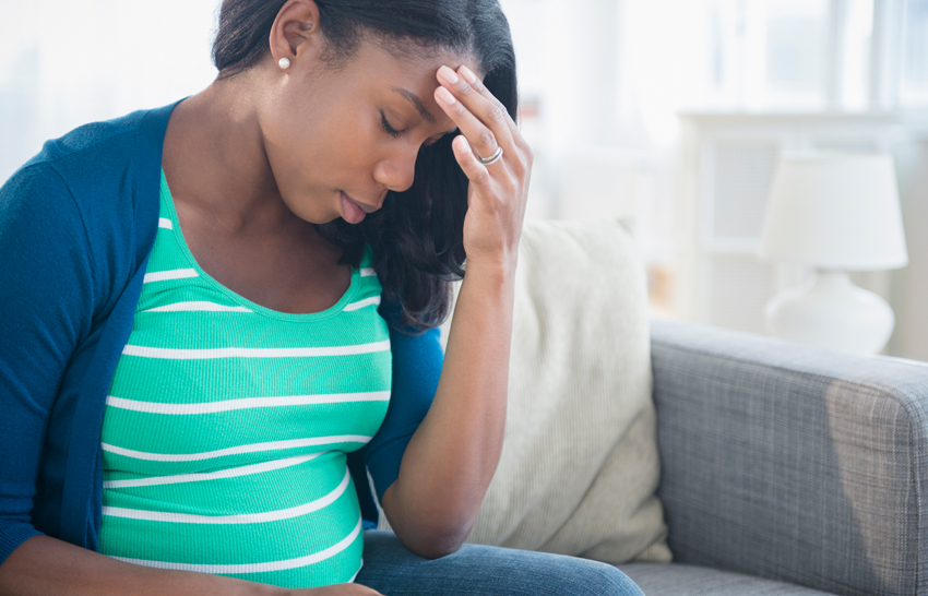 pregnant woman touching her forehead