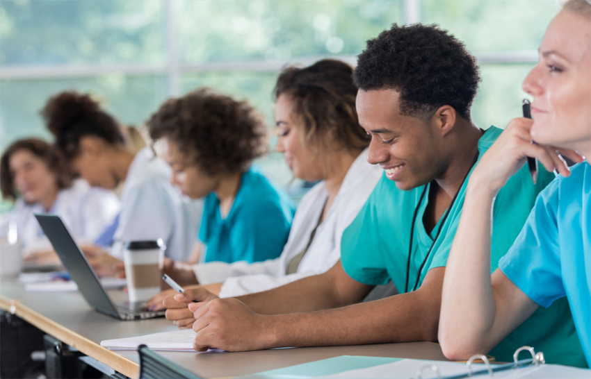 diverse pre med students take notes during class