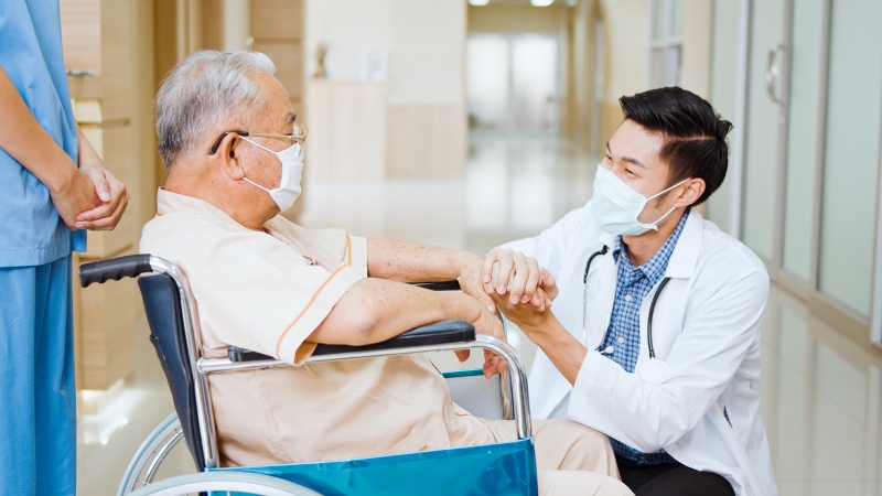 Young doctor holding hand and talking to a senior adult 