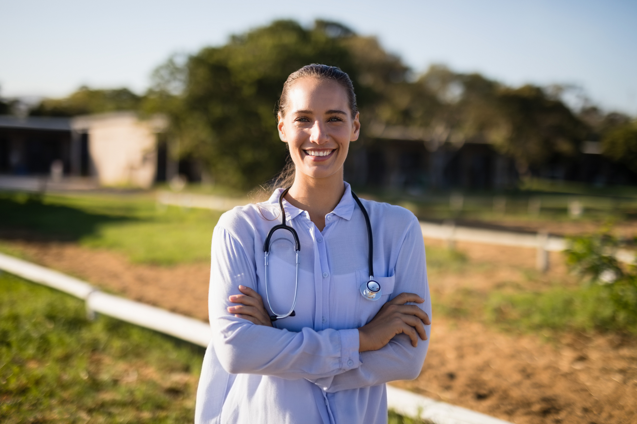 smiling female vet with arms crossed standing at barn