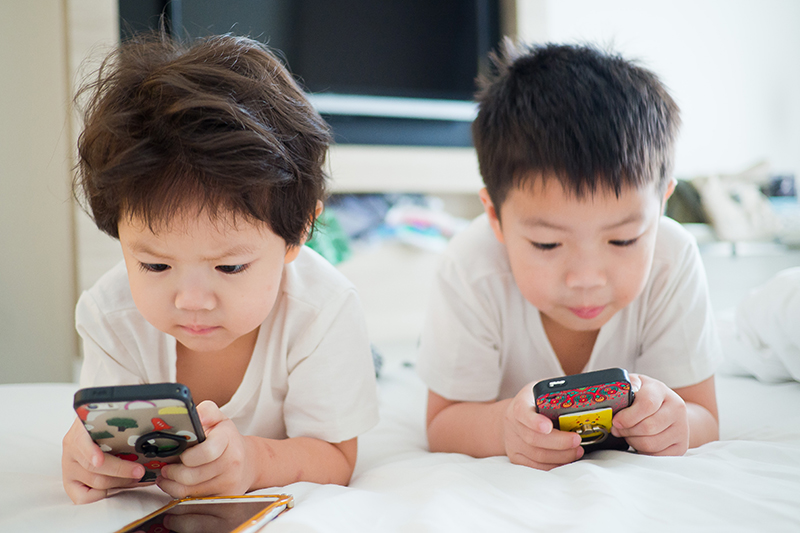 two young children on cell phones