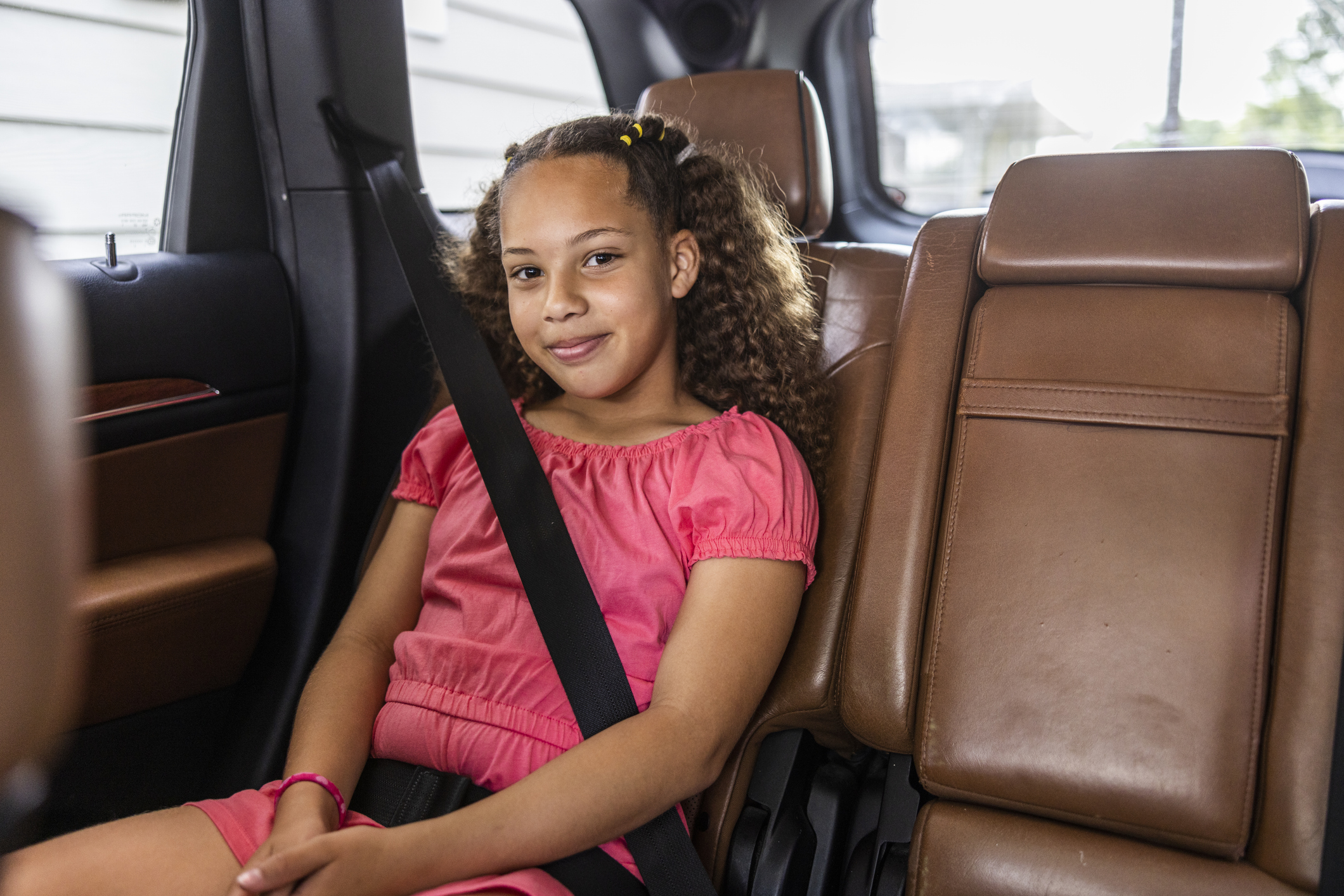 young girl sitting in the back seat of a car