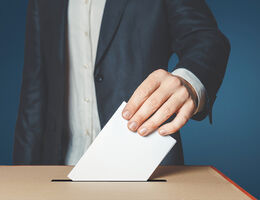 man putting ballot into voting box