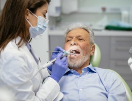 man in dentist chair with woman dentist working on him