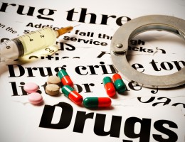 paper with words about drugs on it with handcuffs and drugs