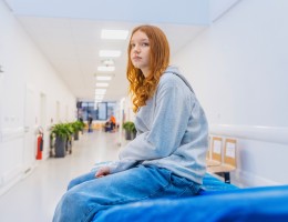 teenage girl sitting on a hospital bed waiting in the lobby
