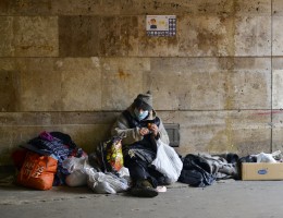 homeless man with his possessions in tunnel