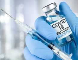 gloved had holding vile of Covid vaccine and syringe
