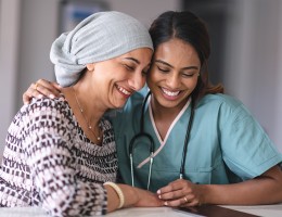 Woman being comforted by doctor. Both have smiles on face.