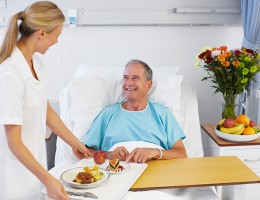 Man in Hospital Bed receiving food from nurse