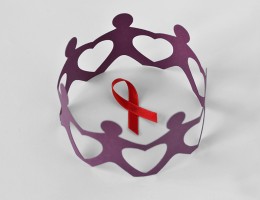 paper cutout of people in circle around red HIV red ribbon