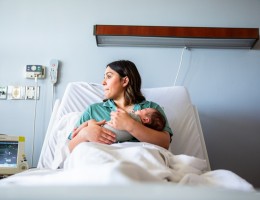 female patient on a hospital bed holding a child in her arms