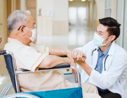 Young doctor holding hand and talking to a senior adult 