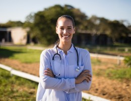smiling female vet with arms crossed standing at barn